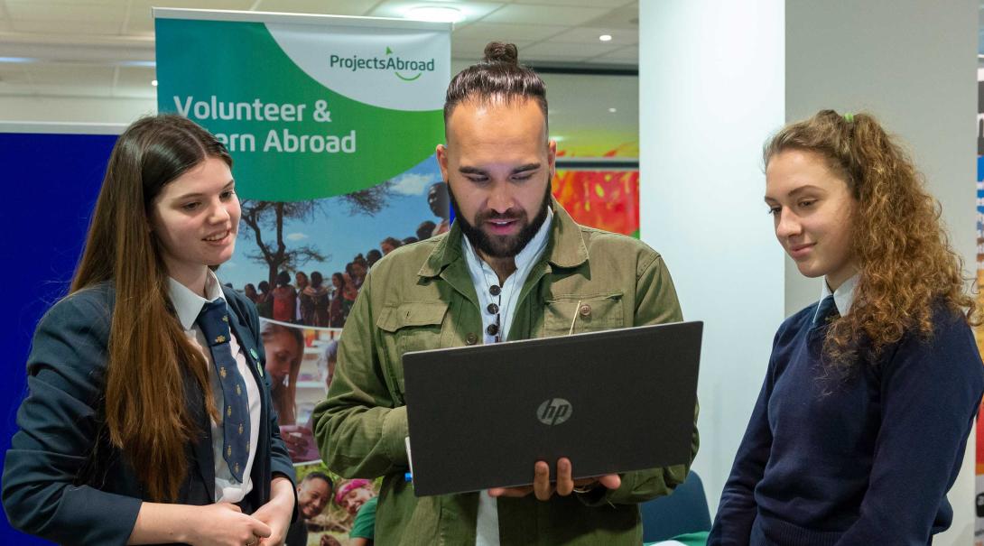 Der Community-Manager mit zwei Studierenden an einer Informationsveranstaltung in London Unser Community-Manager spricht zu zwei Studierenden an einer Infoveranstaltung in London
